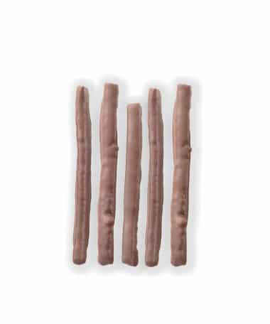 Overhead view of five chocolate-covered strips of orange peel laying on a white background.