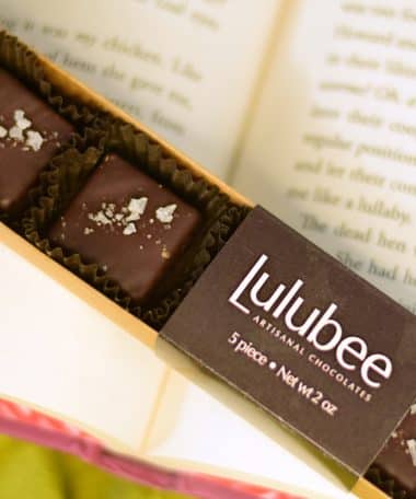 Box of gourmet dark chocolate truffles in a box with a label that reads Lulubee Artisanal Chocolates. Each bonbon is sprinkled with sea salt.