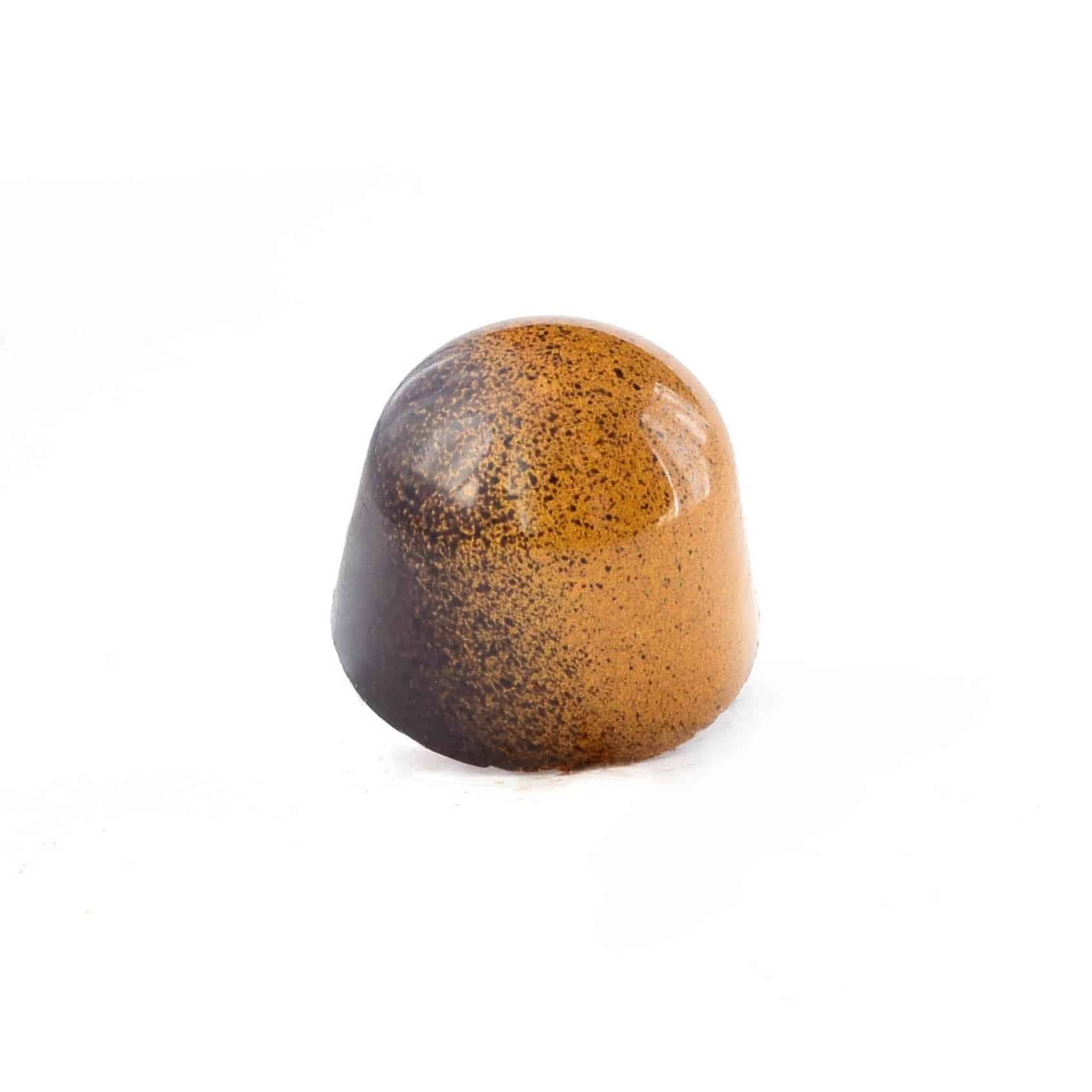 Side view of a tan and brown gourmet chocolate truffle that tastes like brown butter caramel