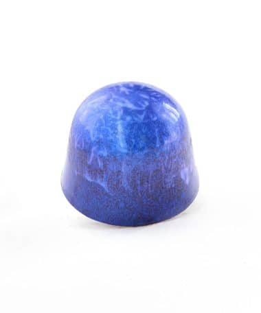 Side view of a bright blue gourmet chocolate truffle with brown swirls; truffle tastes like sweet coconut and almonds