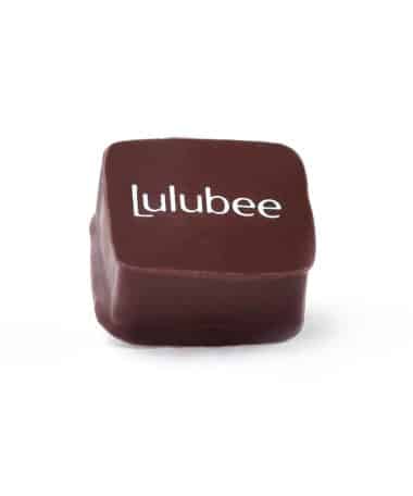 Side view of a gourmet dark chocolate truffle that has the Lulubee logo on it
