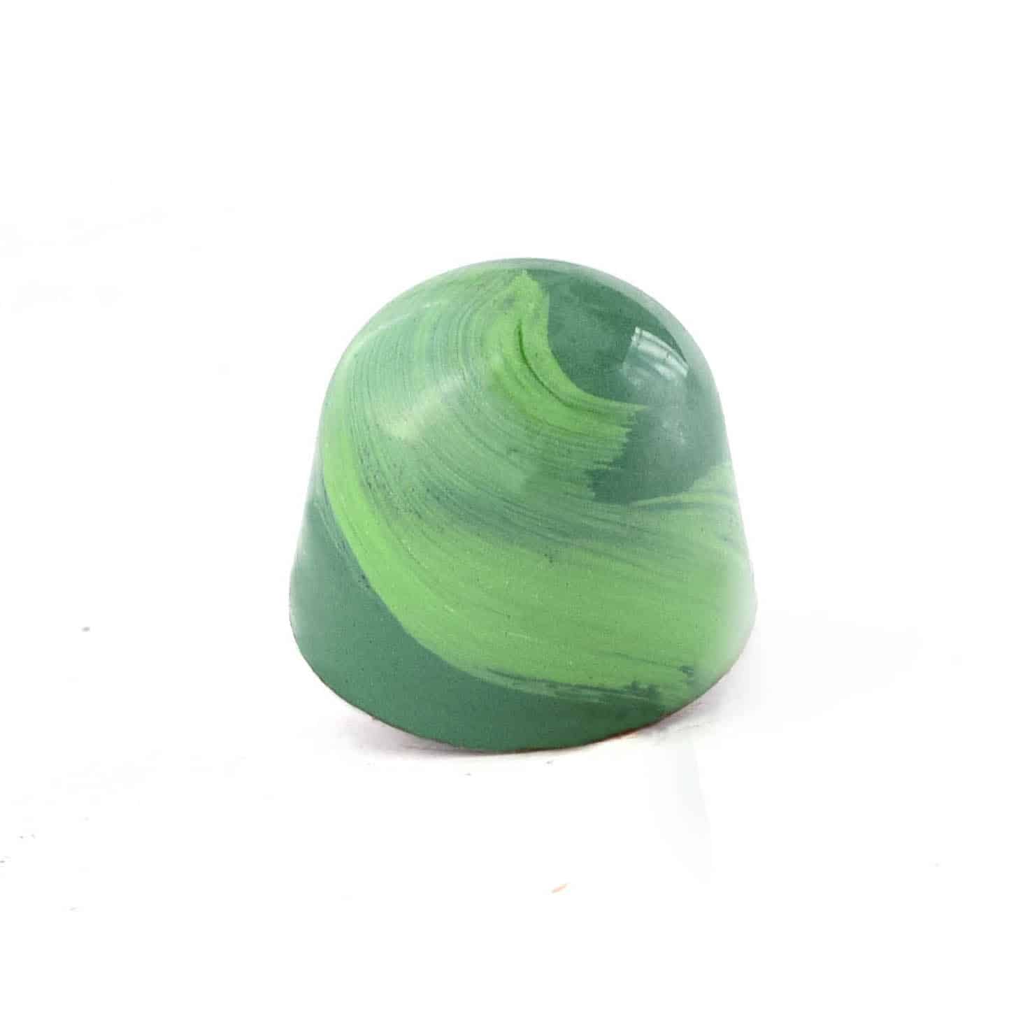 Side view of a green gourmet chocolate truffle with a lighter green brush stroke; truffle tastes like mint