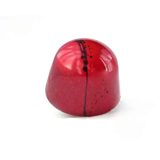 Side view of a red gourmet chocolate truffle with a black stripe; truffle tastes like strawberry and balsamic syrup