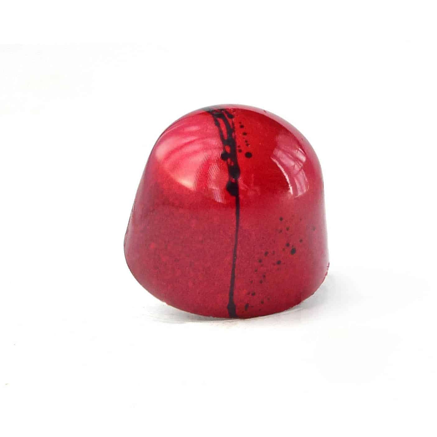 Side view of a red gourmet chocolate truffle with a black stripe; truffle tastes like strawberry and balsamic syrup