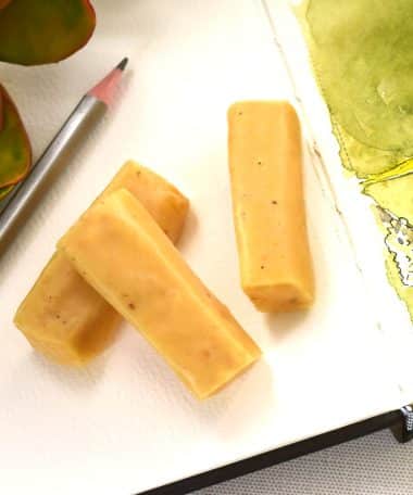 Three pieces of light-yellow colored gourmet cardamom flavored caramels on an open book