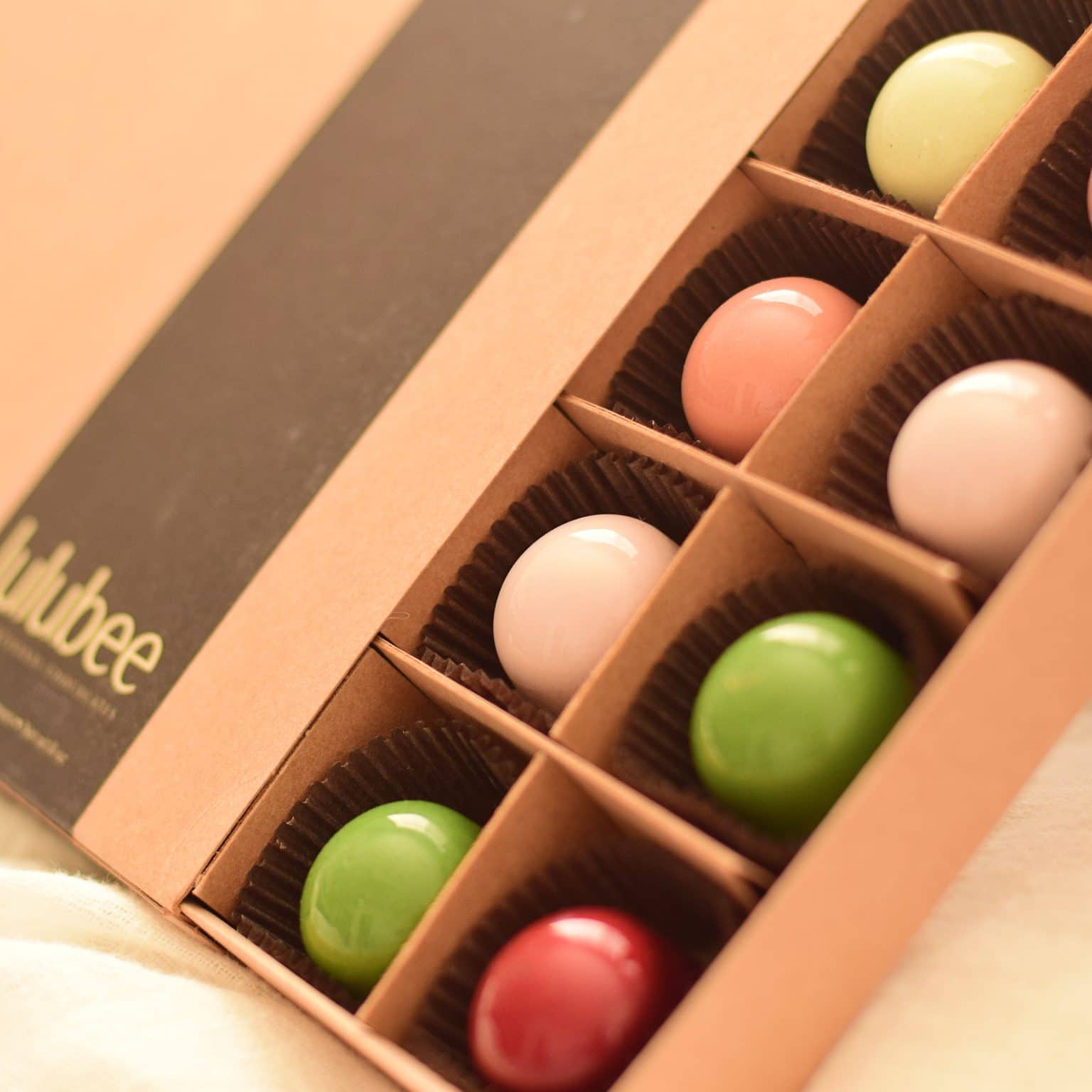 24-piece box of pastel-colored gourmet chocolate truffles in a kraft box with a label that reads Lulubee Artisanal Chocolates