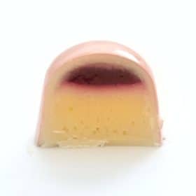 Inside view of a gourmet chocolate truffle that contains a thick layer of lemon ganache and a thin layer of raspberry jelly to taste like raspberry lemonade