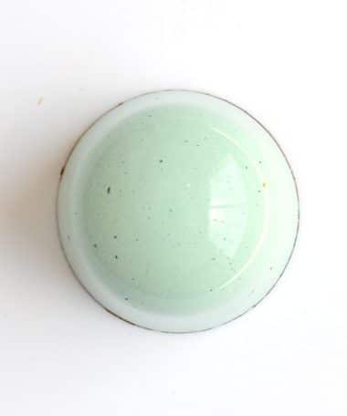 Overhead view of a pale green gourmet truffle that contains dairy-free caramel and a ground almond gianduja