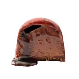 Inside view of a gourmet chocolate truffle that contains a thick layer of strawberry ganache and a thin layer of syrupy balsamic vinegar that is dripping out of the bonbon