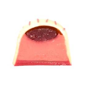 Inside view of a gourmet chocolate truffle that contains a thick layer of raspberry and white chocolate ganache and a thin layer of raspberry jelly