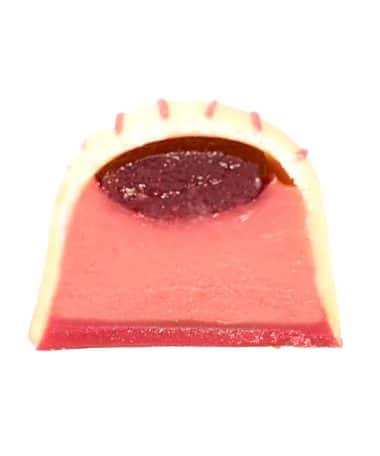 Inside view of a gourmet chocolate truffle that contains a thick layer of raspberry and white chocolate ganache and a thin layer of raspberry jelly