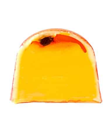 Inside view of a gourmet chocolate truffle that contains a thick layer of passion fruit ganache with a thin layer of passion fruit jam that has one black passion fruit seed
