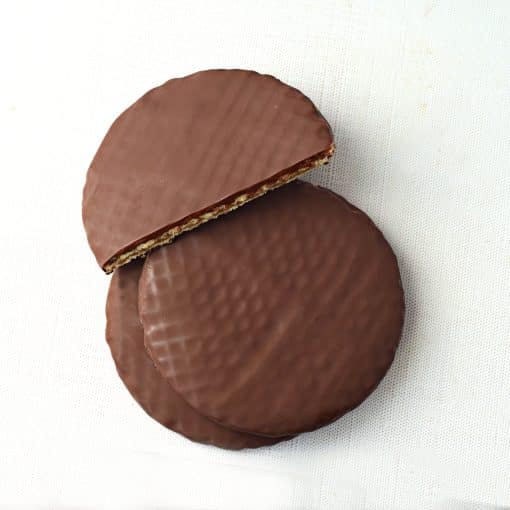 Overhead view of three dark chocolate covered stroopwafels; one is cut in half to reveal the inside