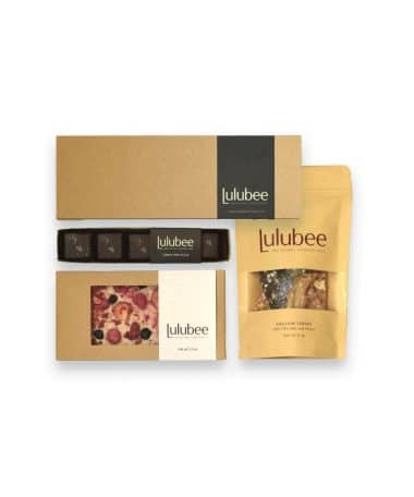 Four packages of artisanal treats in kraft-colored packaging; contain a 12-piece box of bonbons, a 5-piece box of Sea Salt Caramels, an artisanal chocolate bar, and a package of gourmet English toffee.