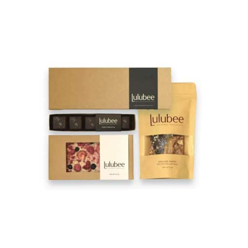 Four packages of artisanal treats in kraft-colored packaging; contain a 12-piece box of bonbons, a 5-piece box of Sea Salt Caramels, an artisanal chocolate bar, and a package of gourmet English toffee.