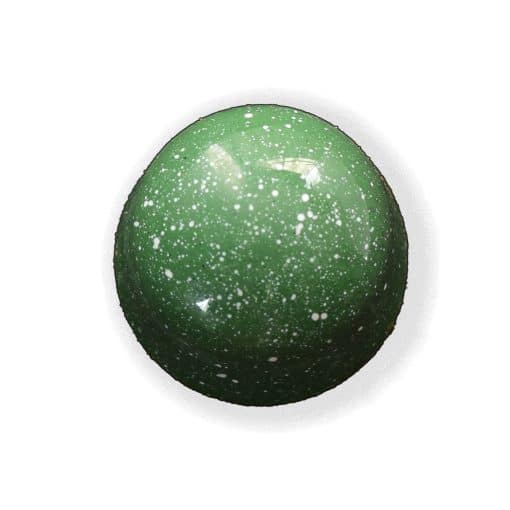 Overhead view of a green gourmet truffle with white speckles that contains a layer of handcrafted cherry jelly atop a house-ground pistachio ganache
