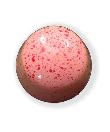 Overhead view of a pink gourmet truffle with white speckles that contains a fresh mint ganache and crunchy peppermint candy