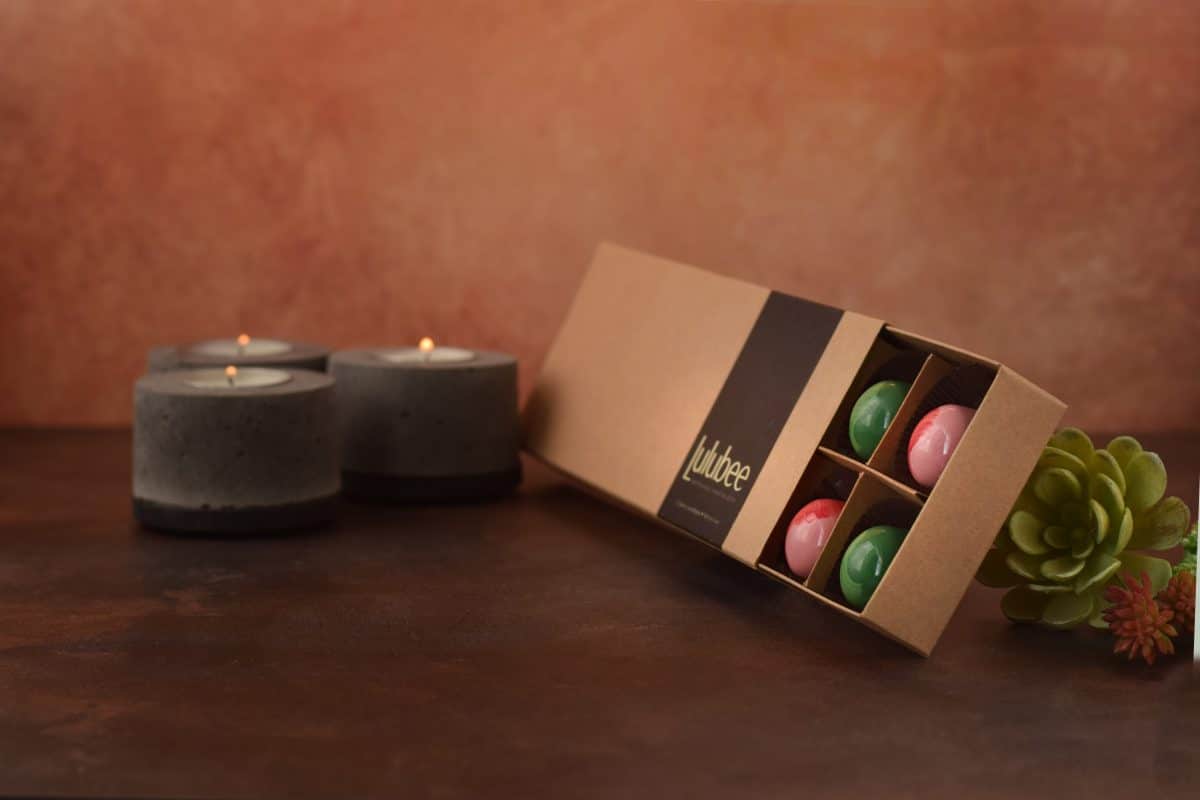 Box of assorted gourmet box of chocolates next to three candles