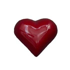 Overhead view of a cherry-red colored, heart-shaped bonbon that is filled with a Brown Butter Caramel