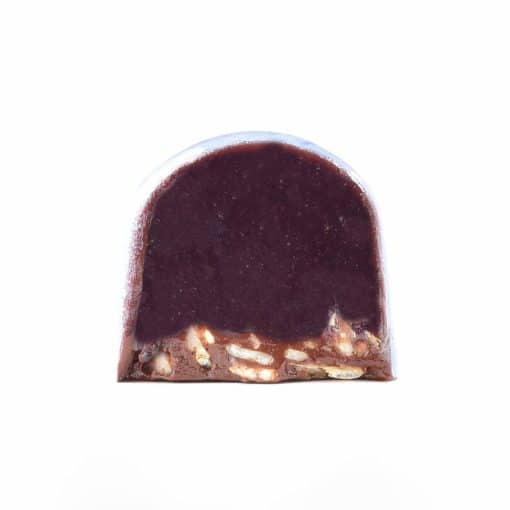 Inside view of a gourmet truffle that contains a thick dark blueberry caramel layer and a thin oat crisp layer