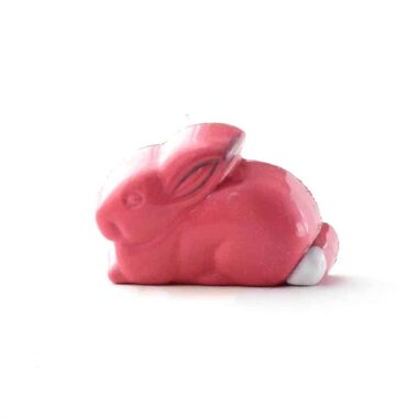 Side view of a rose pink, rabbit-shaped gourmet chocolate truffle filled with handcrafted peanut butter