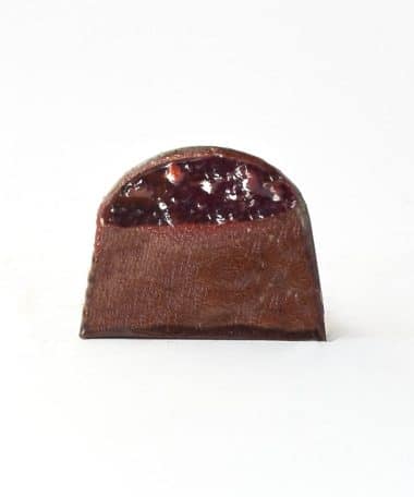 Inside view of a gourmet chocolate truffle with a layer of cherry jelly and dark chocolate ganache