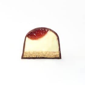 Inside view of a gourmet chocolate truffle with a layer of handcrafted strawberry, cheesecake filling, and graham cracker crust