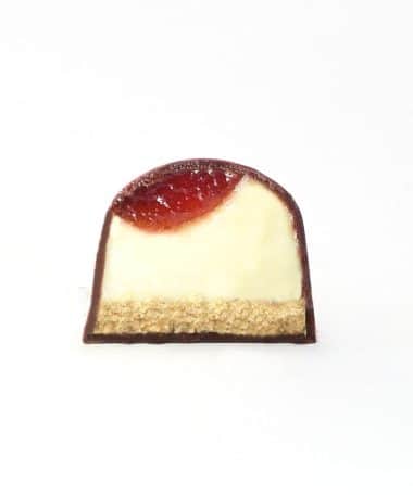 Inside view of a gourmet chocolate truffle with a layer of handcrafted strawberry, cheesecake filling, and graham cracker crust