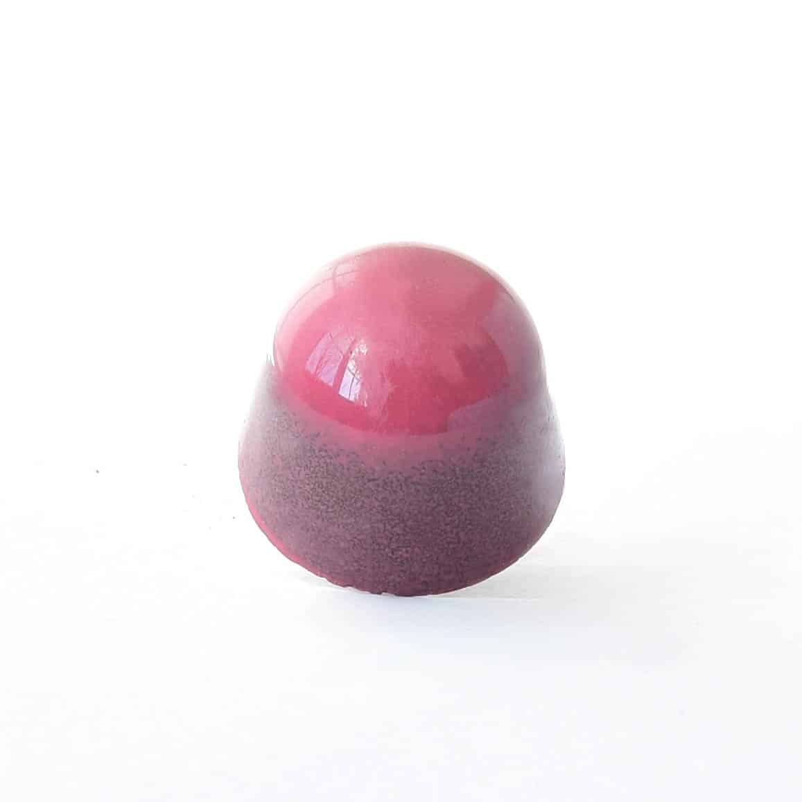 Berry-colored gourmet chocolate truffle that tastes like strawberry cheesecake