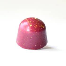 Fall-red gourmet chocolate truffle with orange and yellow dots splattered on it