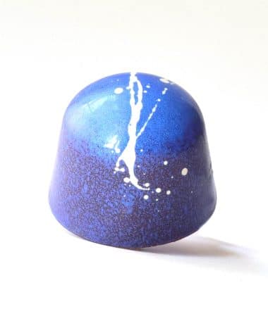 Brilliant blue gourmet chocolate truffle with a white splatter stripe down the middle