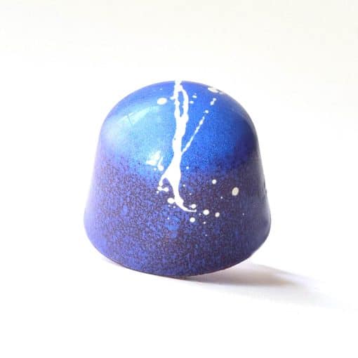 Brilliant blue gourmet chocolate truffle with a white splatter stripe down the middle