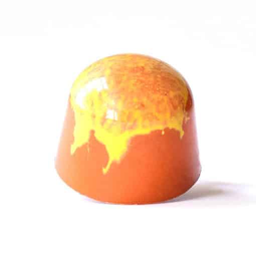 Orange gourmet chocolate truffle with yellow drips down the side