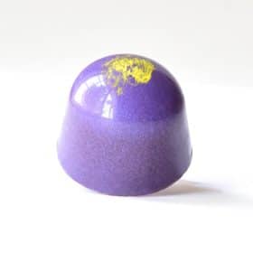 Purple gourmet chocolate truffle with a yellow-green dot on top