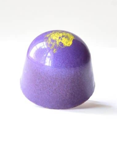 Purple gourmet chocolate truffle with a yellow-green dot on top